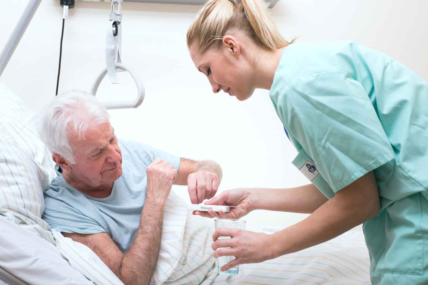 Eine Krankenschwester spricht mit einem älteren Mann in einem Krankenhausbett.