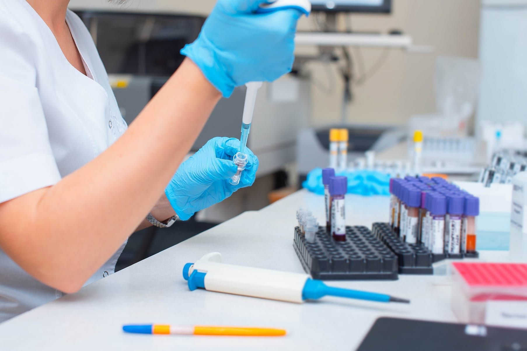 Lab technician handling samples beside test tubes in a clinical lab