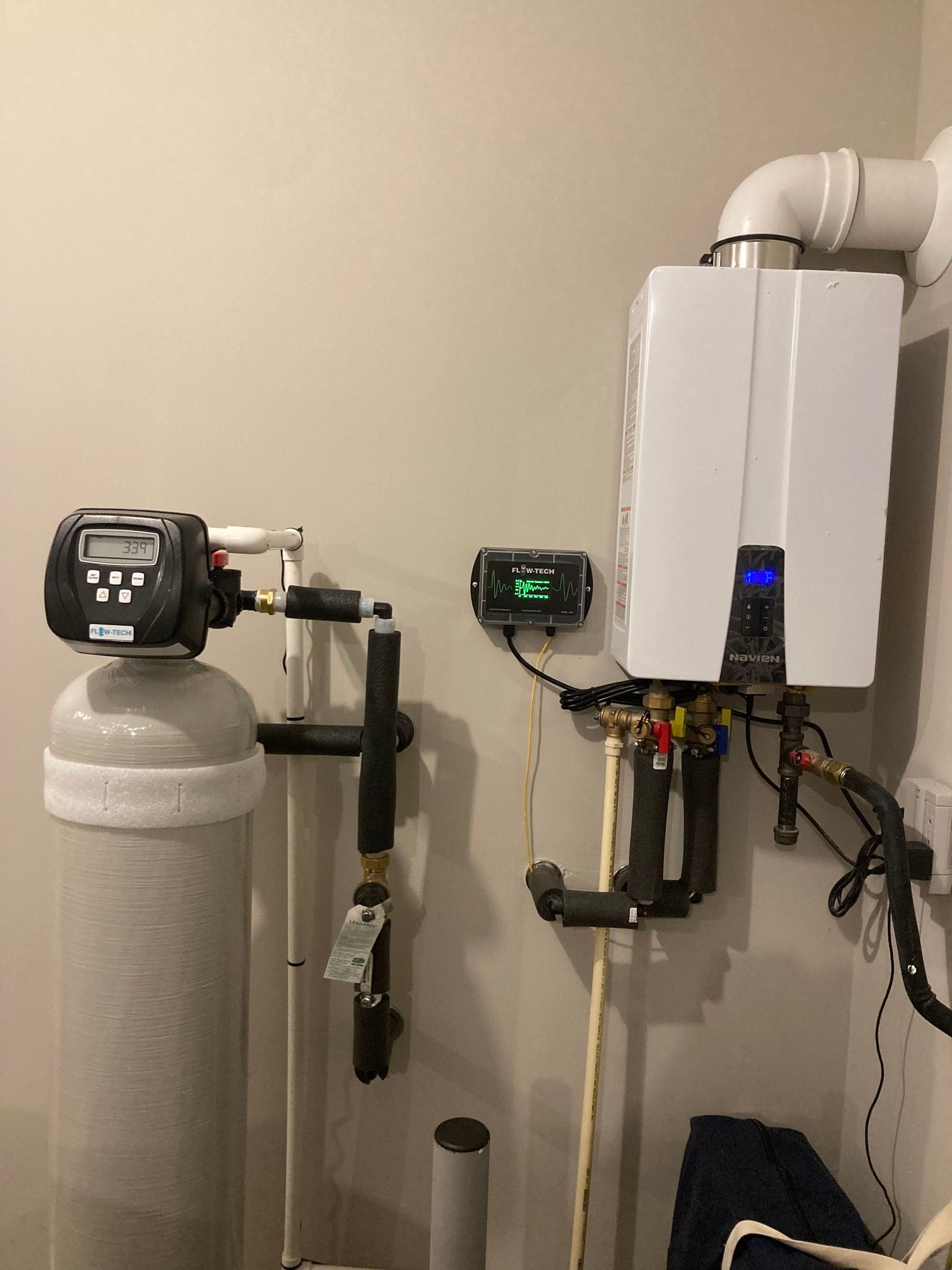 Water softener and tankless water heater mounted on a wall. Plumbing and control panels visible.