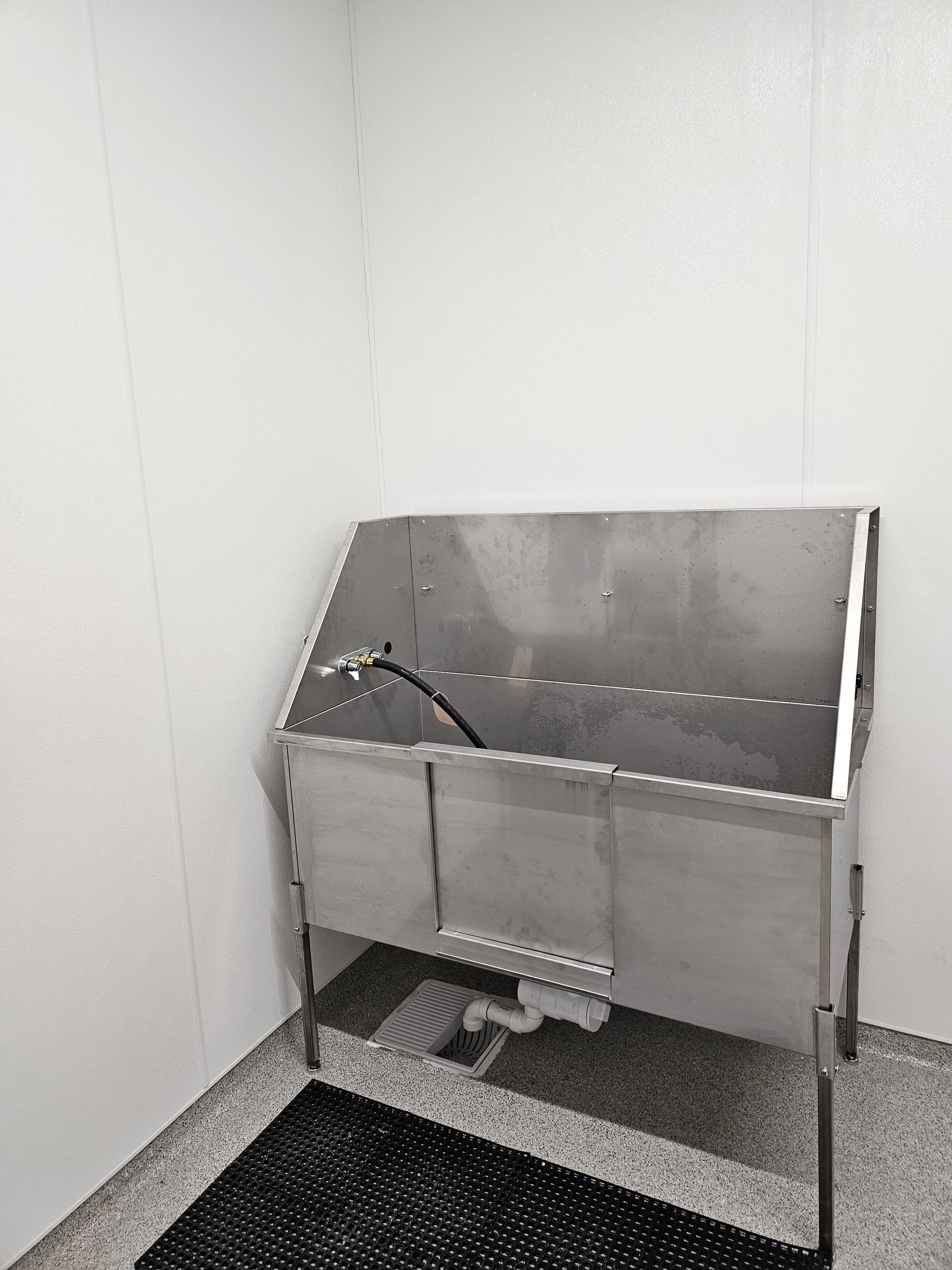 Stainless steel pet wash basin in a corner.