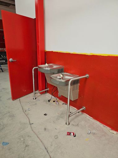 Pipes in red, white, and gray, running overhead in an industrial setting, alongside a metal staircase.