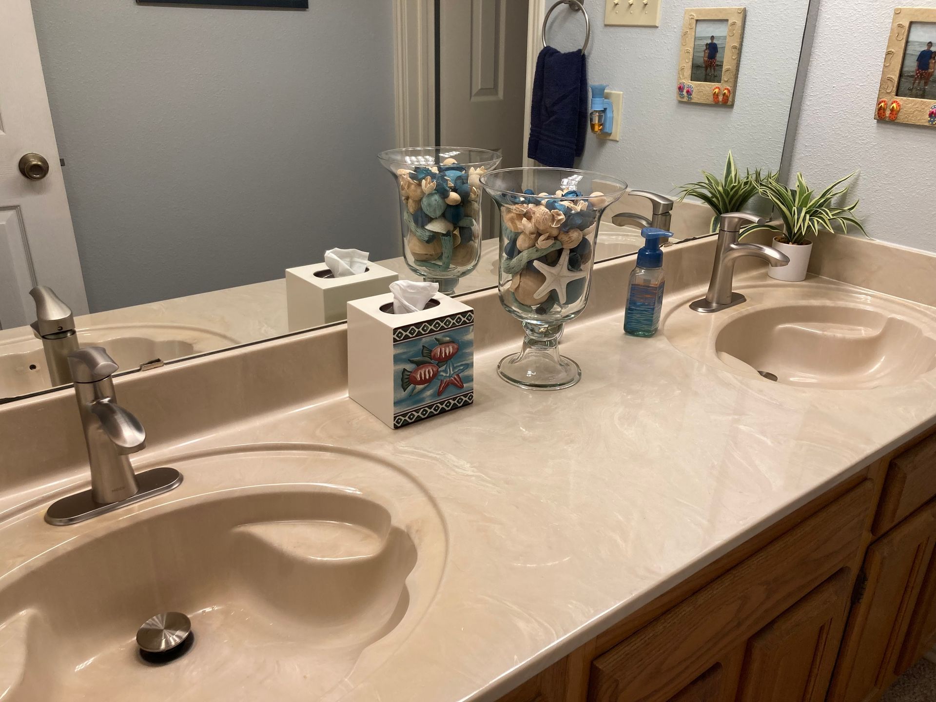 Bathroom with double sinks, seashell decor, and a large mirror.