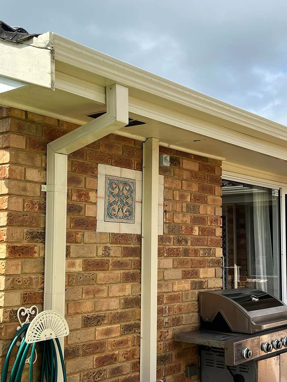 A Hose is Hanging on the Side of a Brick House Next to a Grill — Gutterworx in Wamberal, NSW