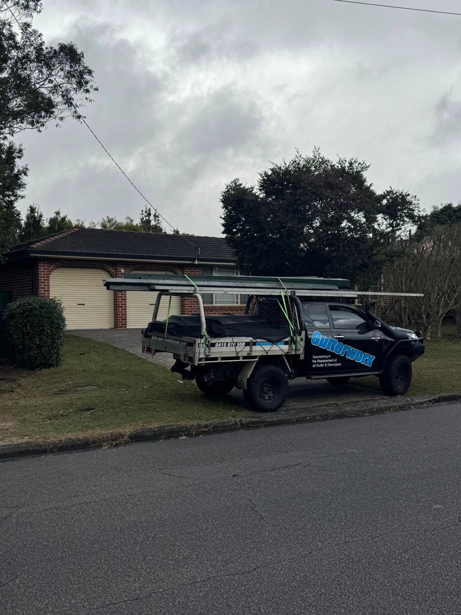 Golf cart with blue cover parked in front of a house on a cloudy suburban street — Gutterworx in Wamberal, NSW