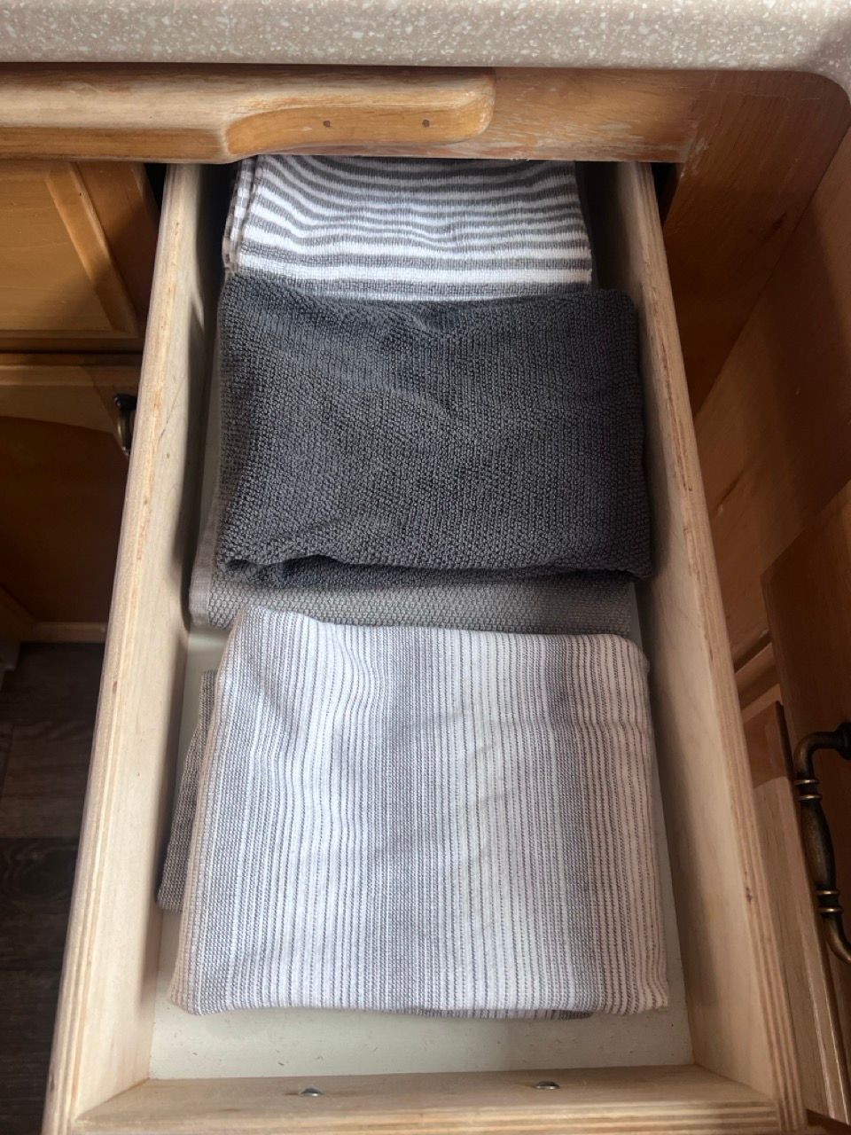 A drawer filled with clothes and towels in a kitchen.