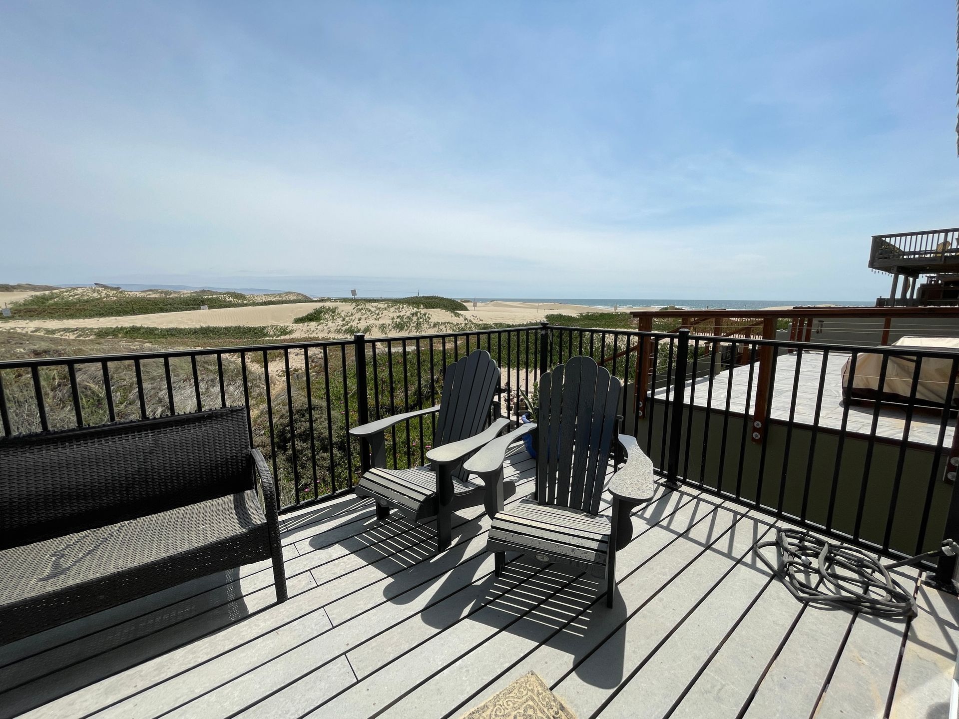 A deck with two chairs and a bench with a view of the ocean