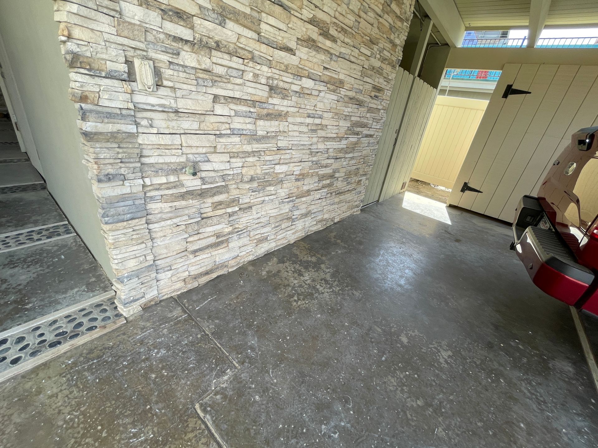 A car is parked in a garage next to a stone wall.