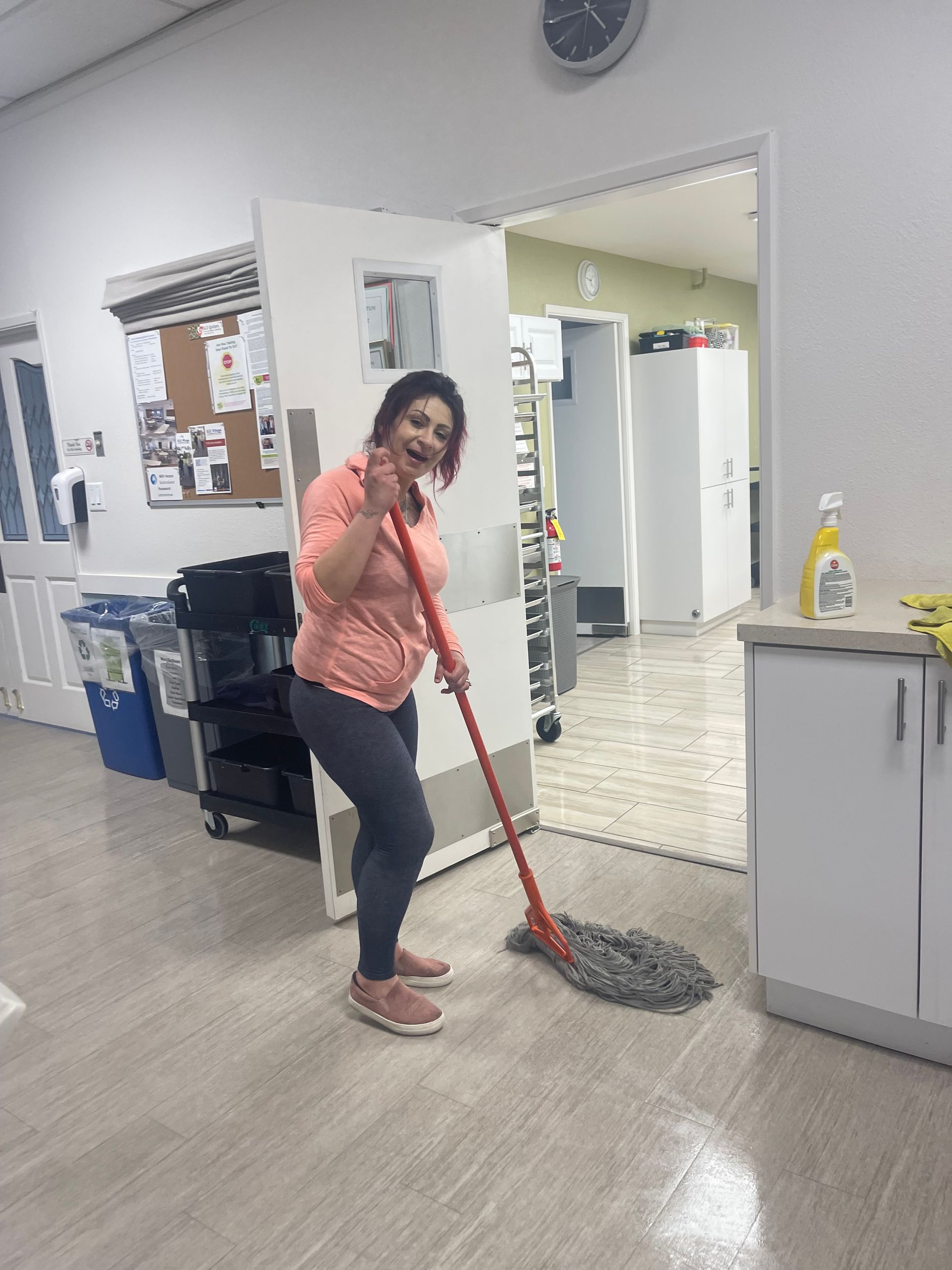 A woman in a pink shirt is mopping the floor