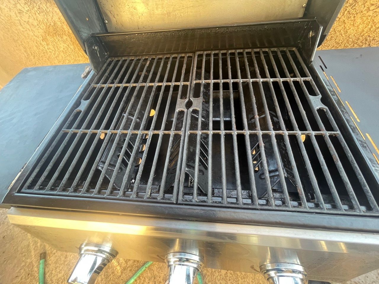 A grill with a hose attached to it is sitting on a table.