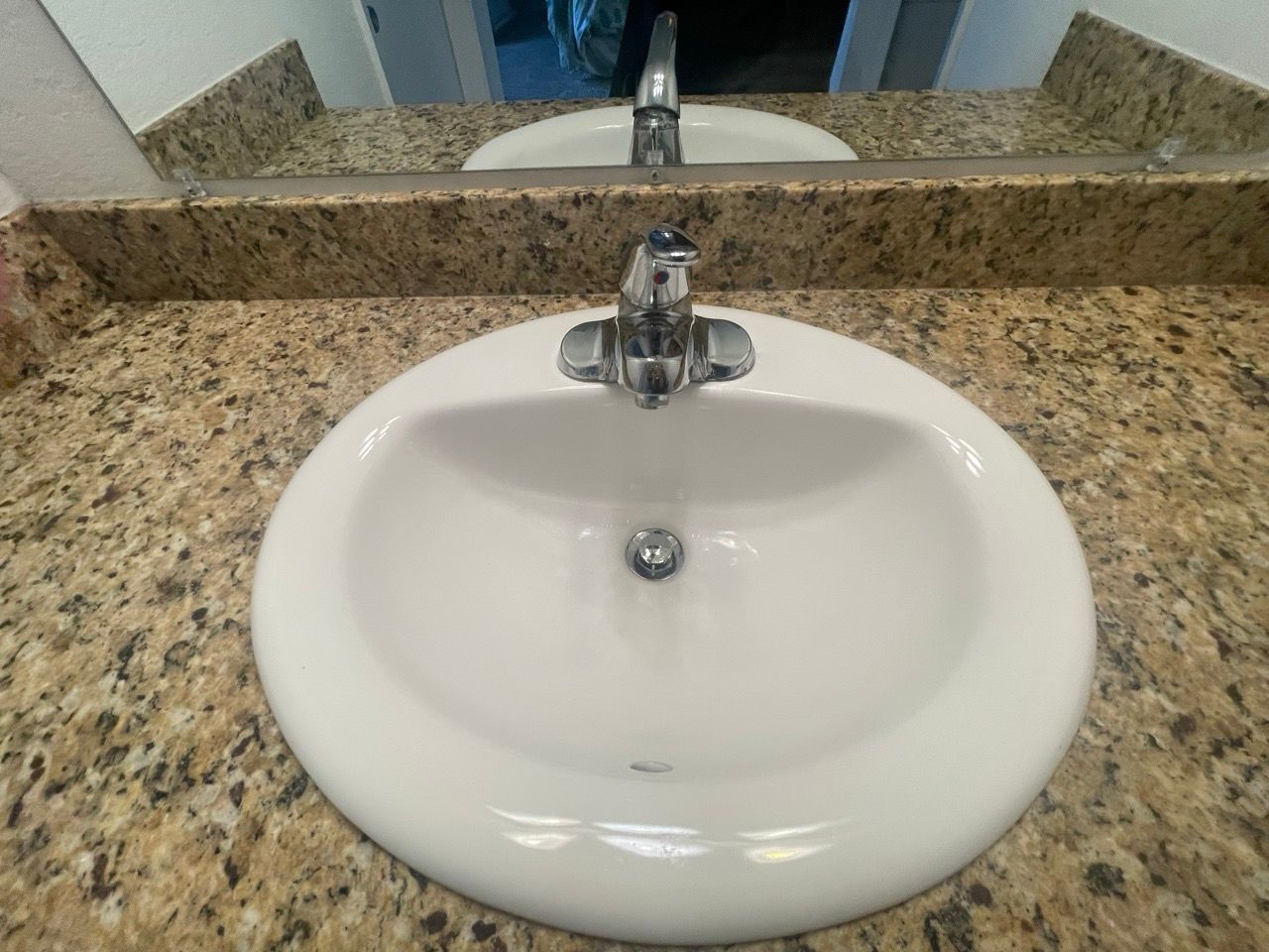 A bathroom sink with a faucet and a mirror.