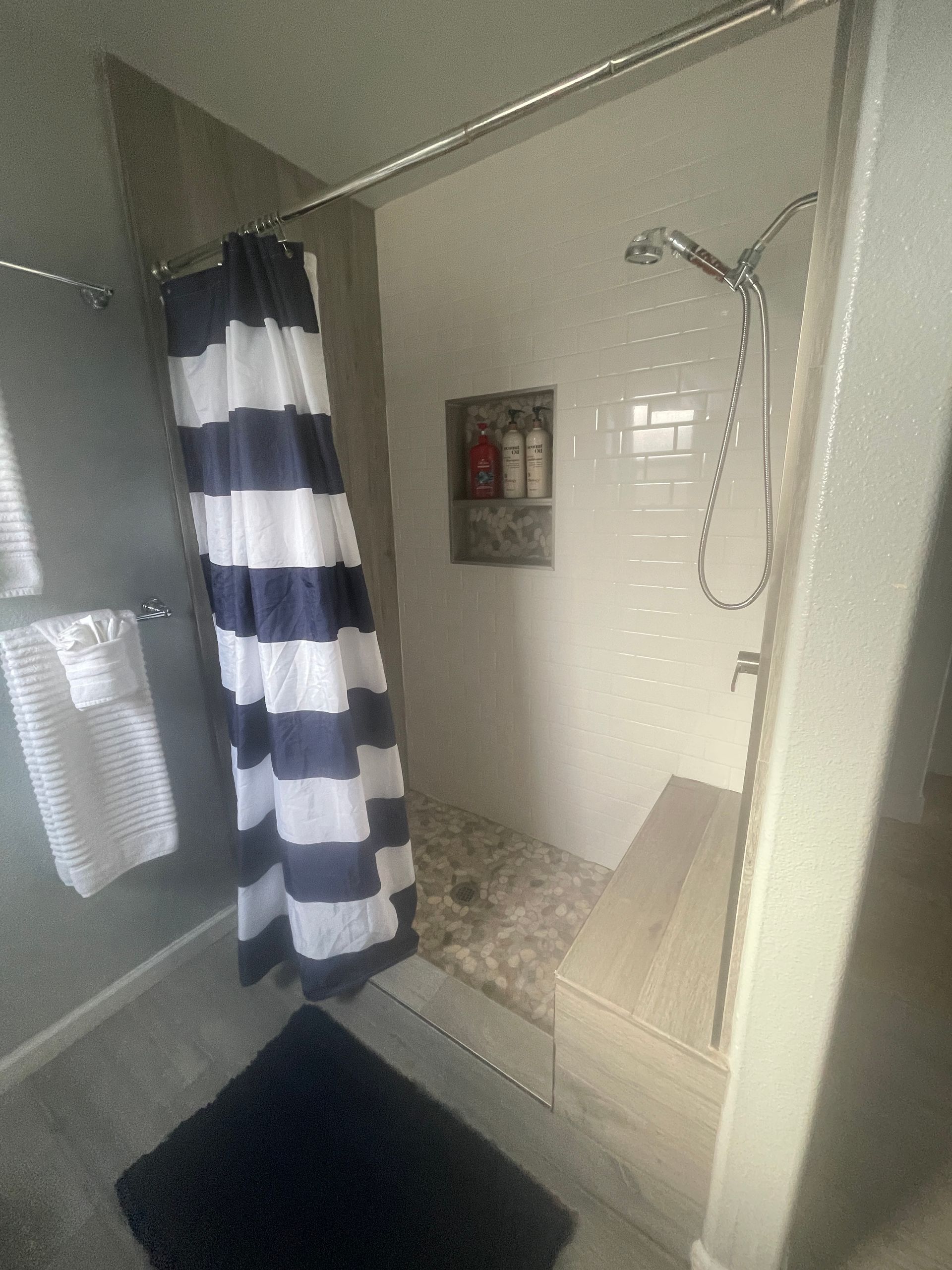 A bathroom with a shower and a striped shower curtain.