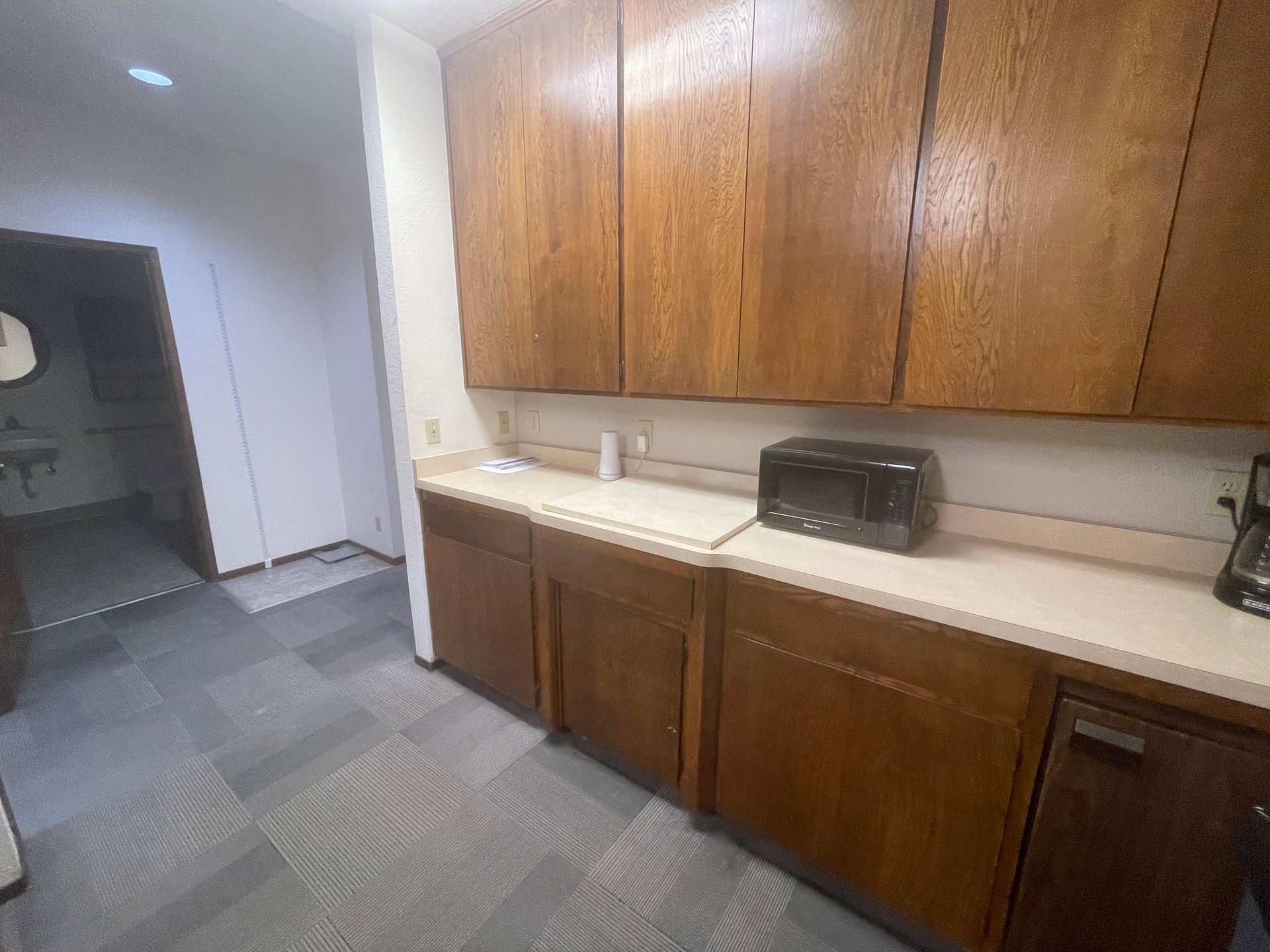 A kitchen with wooden cabinets , a microwave , and a coffee maker.