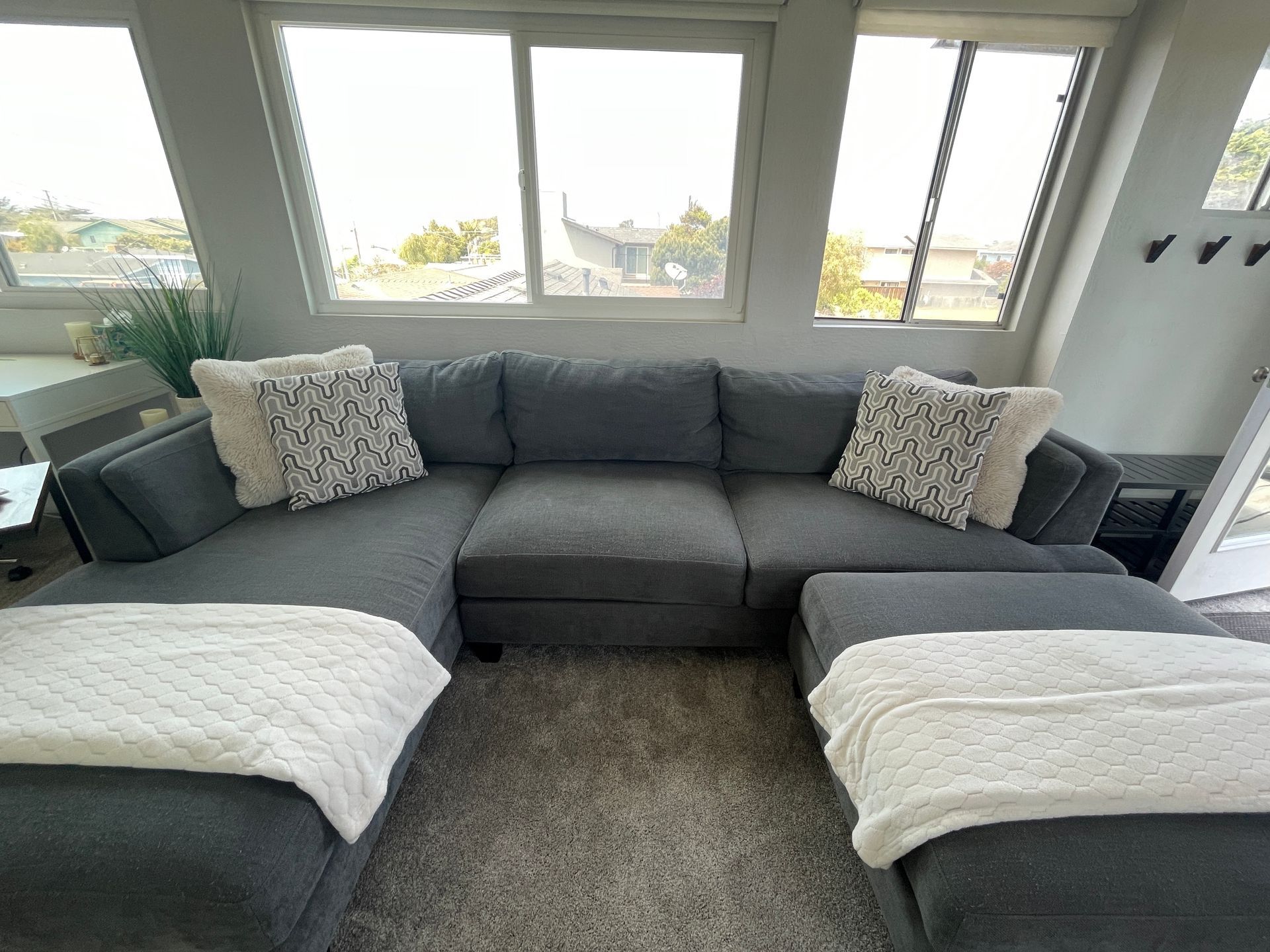 A living room with a large sectional couch and two ottomans.