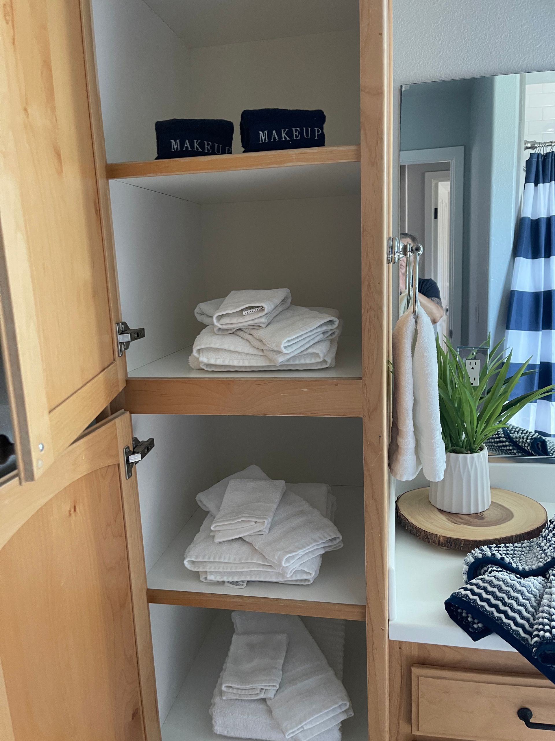 A bathroom with a stack of towels on the shelves