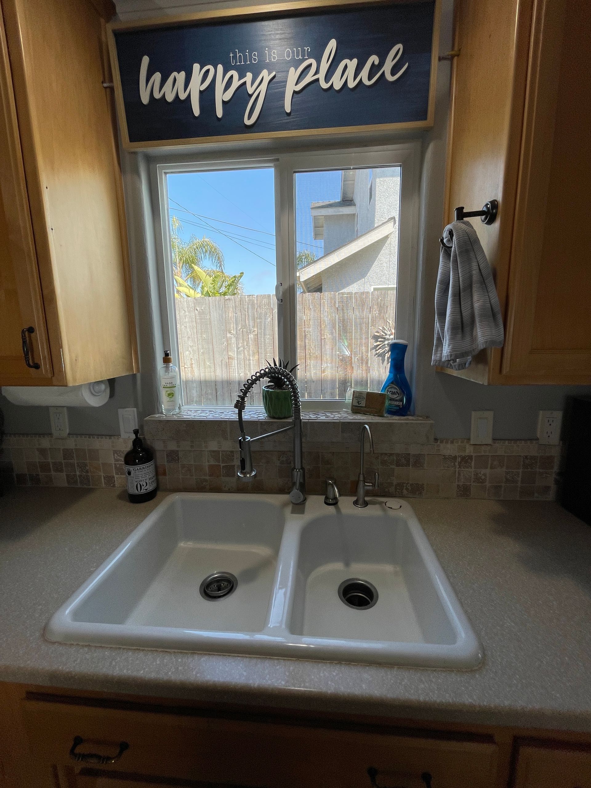 A kitchen sink with a sign above it that says happy place