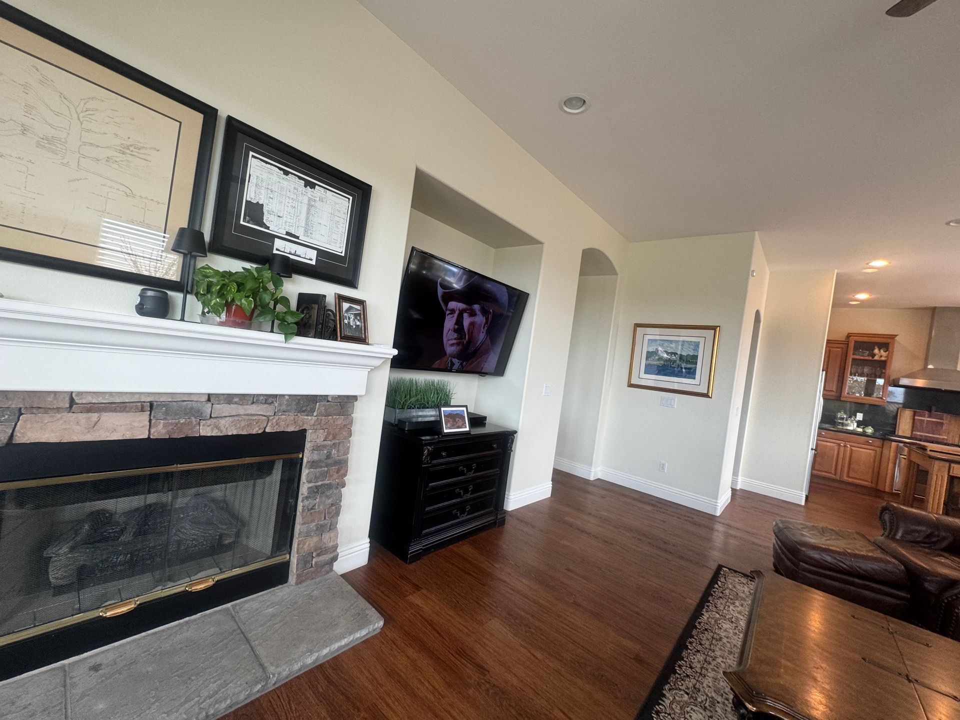 Living room with fireplace, TV, black dresser, and hardwood floors.