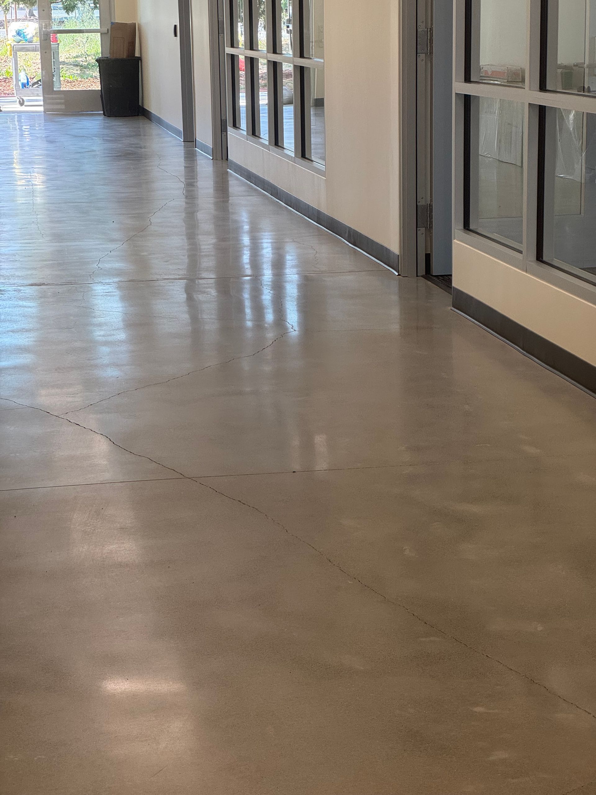 Long hallway with polished concrete floor, windows on one side, light streaming in.