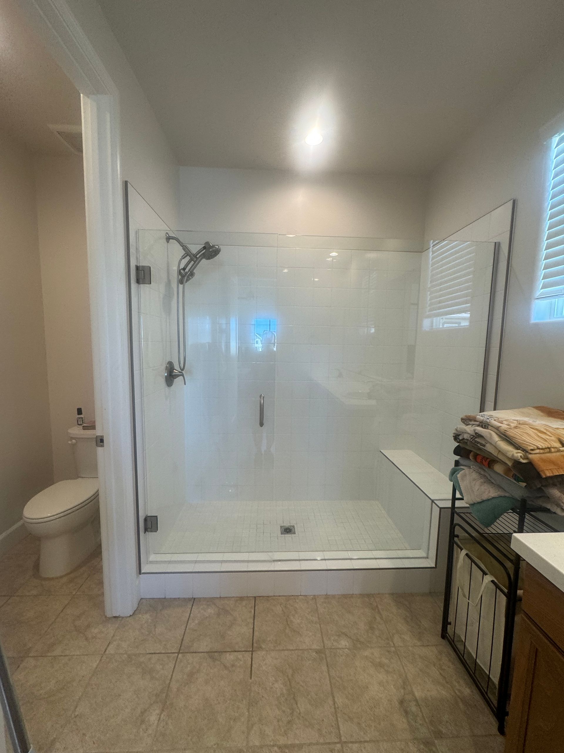 Bathroom with a large white shower, toilet, and a cabinet.