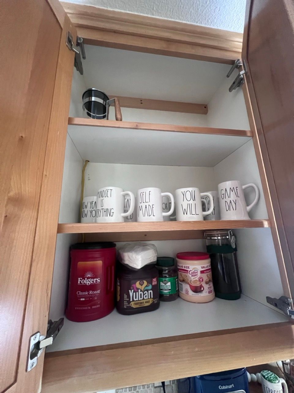 A kitchen cabinet with a few mugs on the shelves