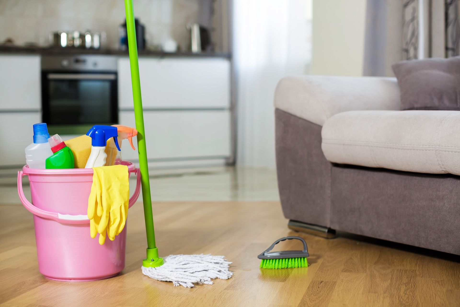 A mop , bucket , gloves and cleaning supplies are on the floor in a living room.