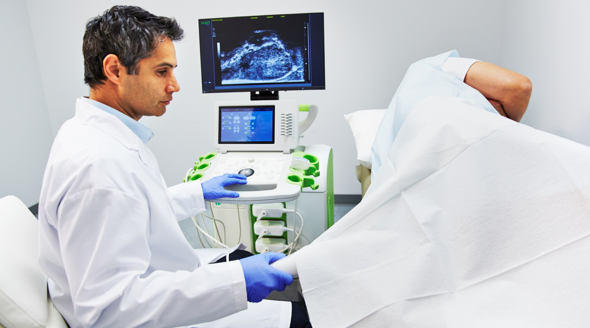 A doctor is giving a patient an ultrasound in a hospital.