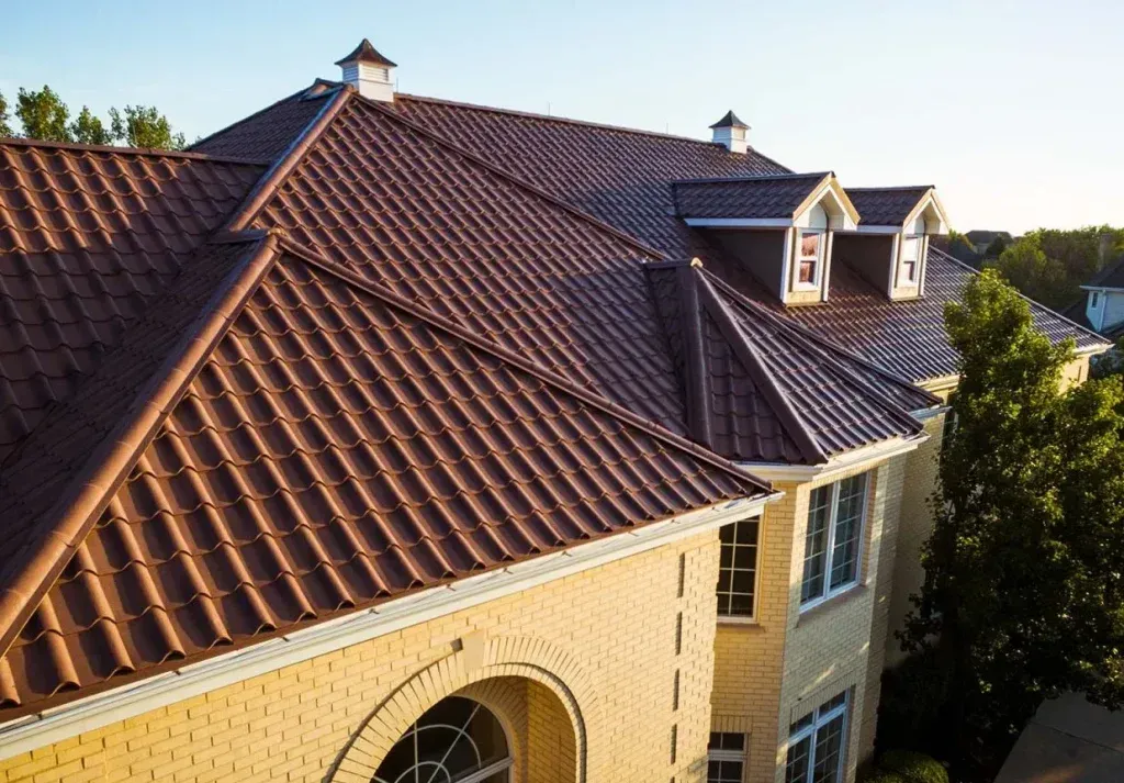 Sunlit red-tiled roof with two dormer windows on a beige house