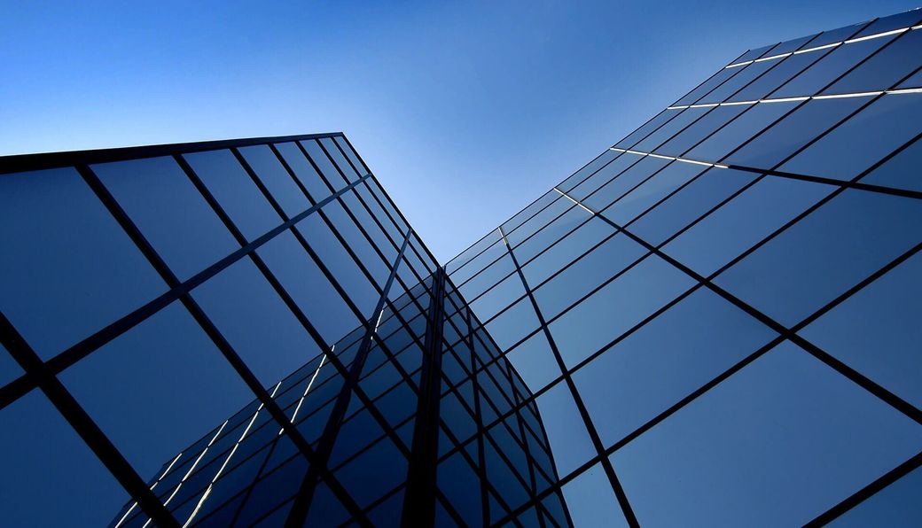 Reflective blue glass skyscrapers viewed from below against a clear sky