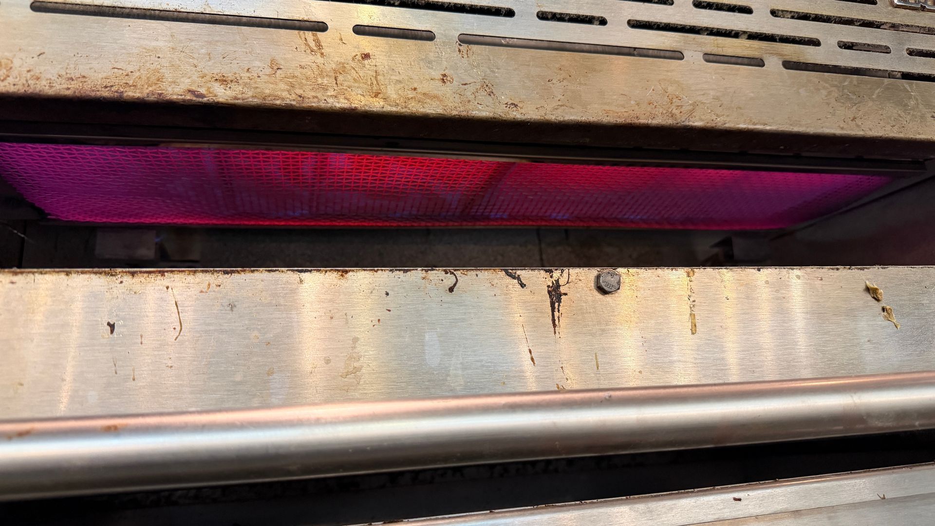Close-up of a metal surface with a purple light glowing behind a narrow horizontal opening