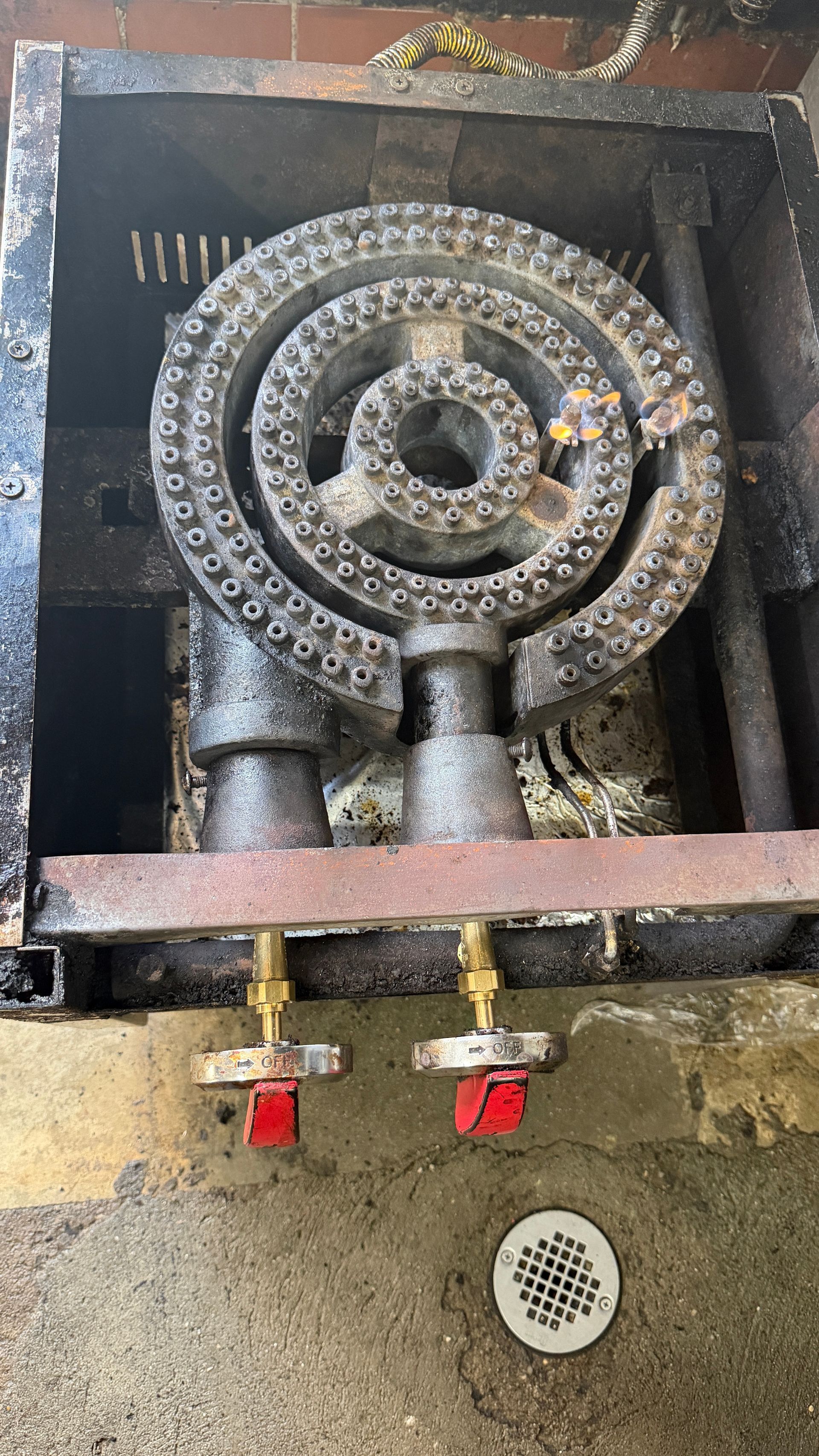 Metal gas burner assembly with circular burner rings and red valve handles in a wall cavity