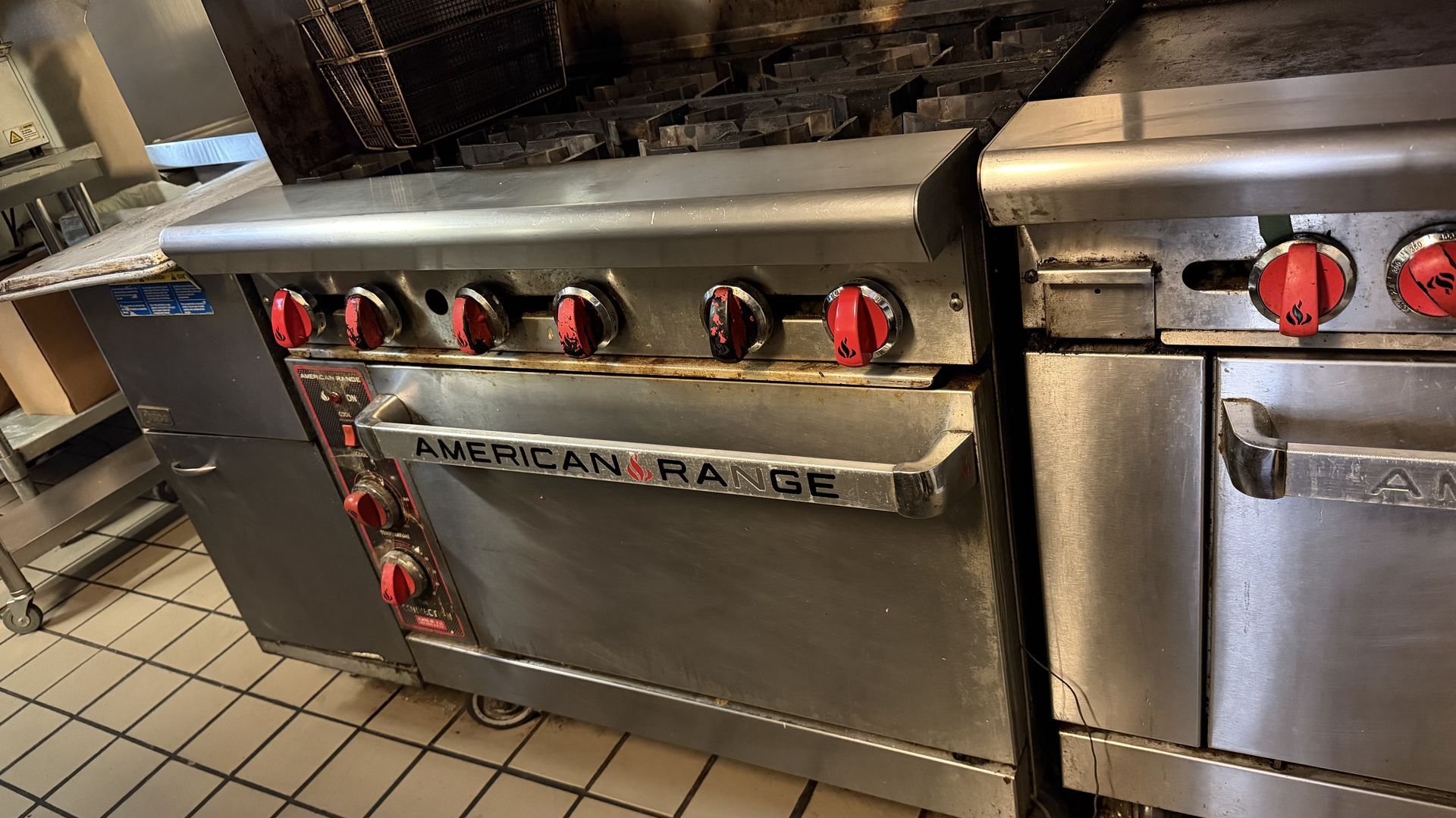 Stainless steel commercial grill with red knobs in a restaurant kitchen
