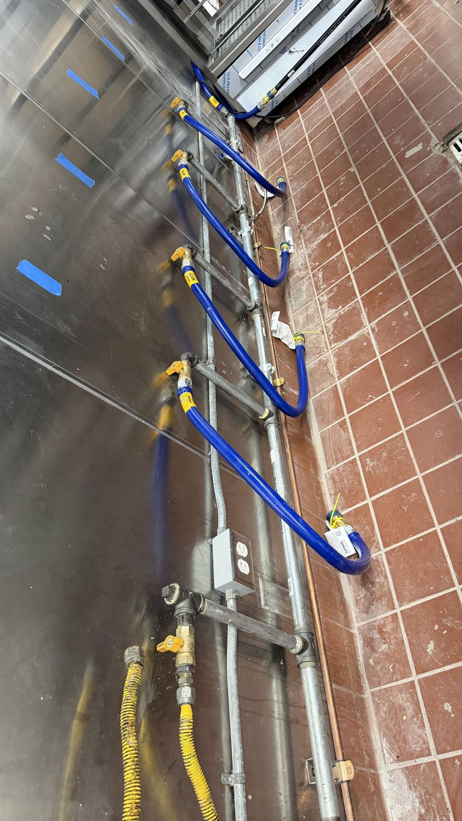 Industrial pipes with six colorful valve wheels on a teal pipeline system