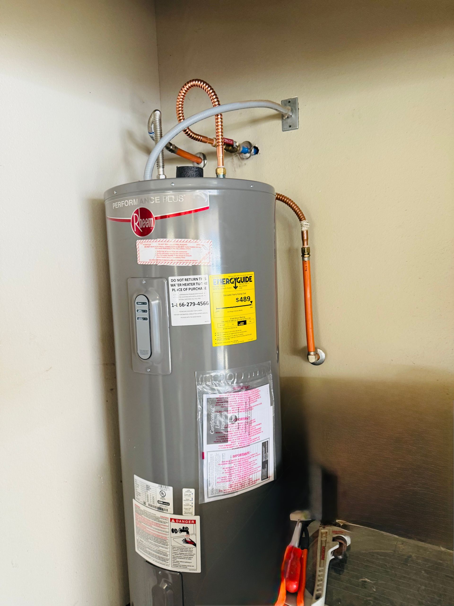 Water heater with pipes and labels in a utility closet