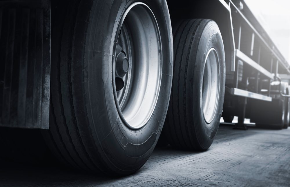Close-up of semi-truck wheels on a paved road, dark tones.