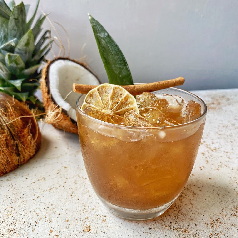 A glass of iced tea with a slice of lemon and cinnamon sticks.