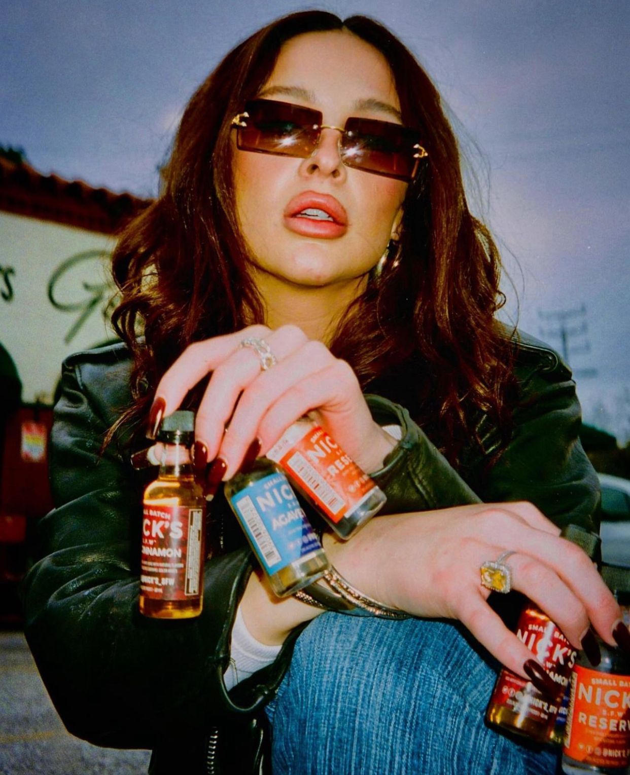 A woman wearing sunglasses is holding bottles of nicotine