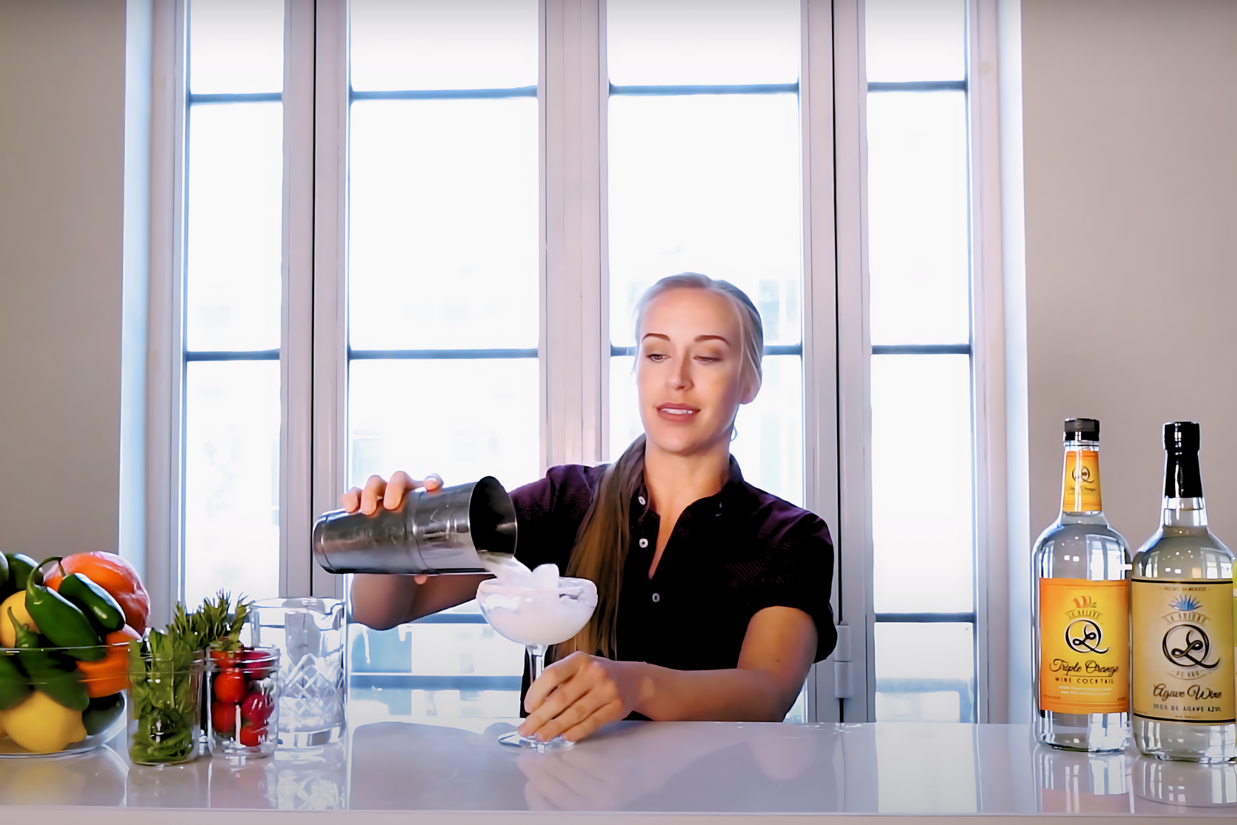 A woman is pouring a drink into a martini glass.