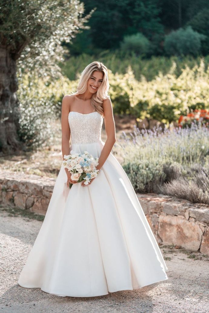 The bride is wearing a white wedding dress and holding a bouquet of flowers.