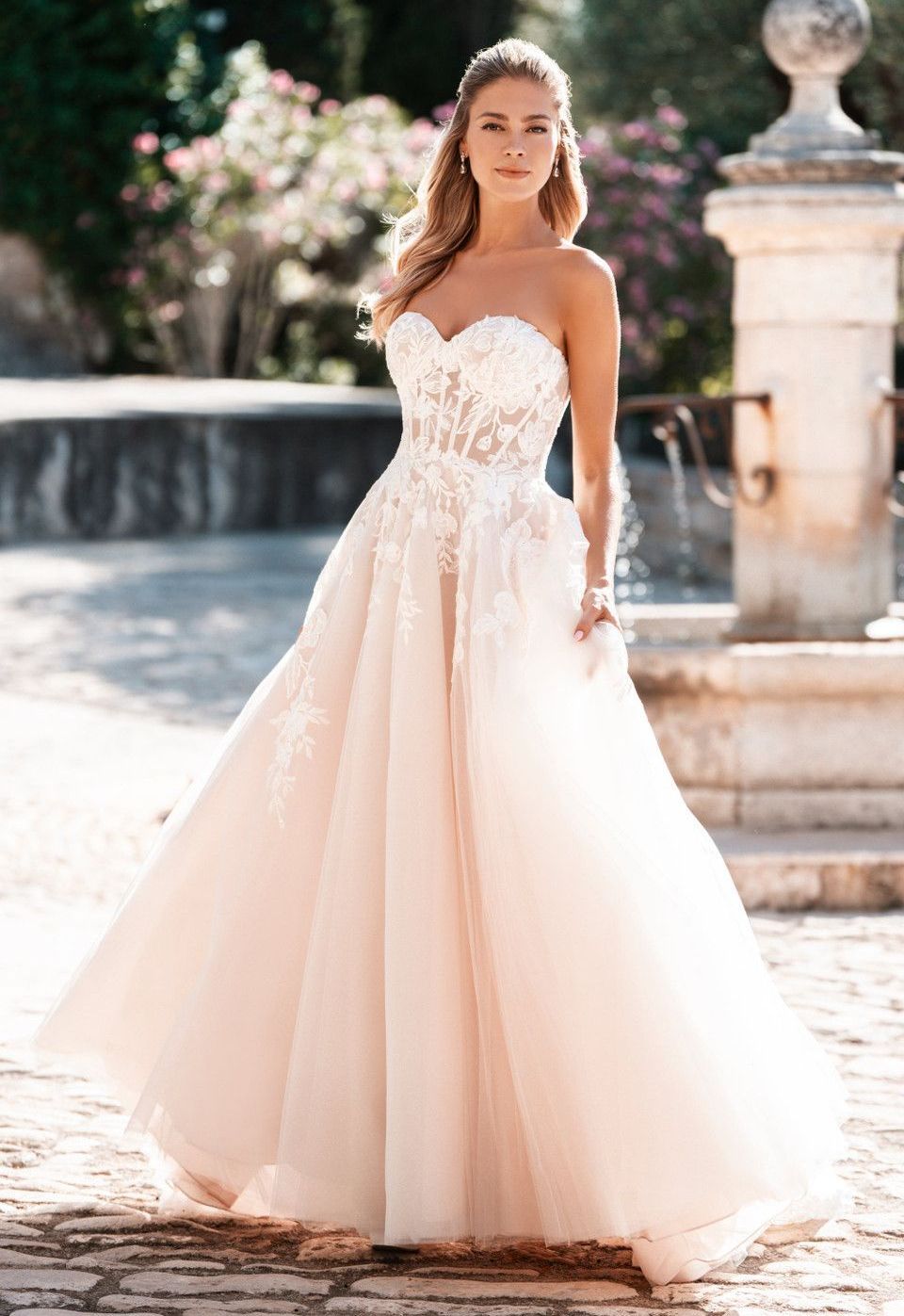 A woman in a wedding dress is standing in front of a fountain.