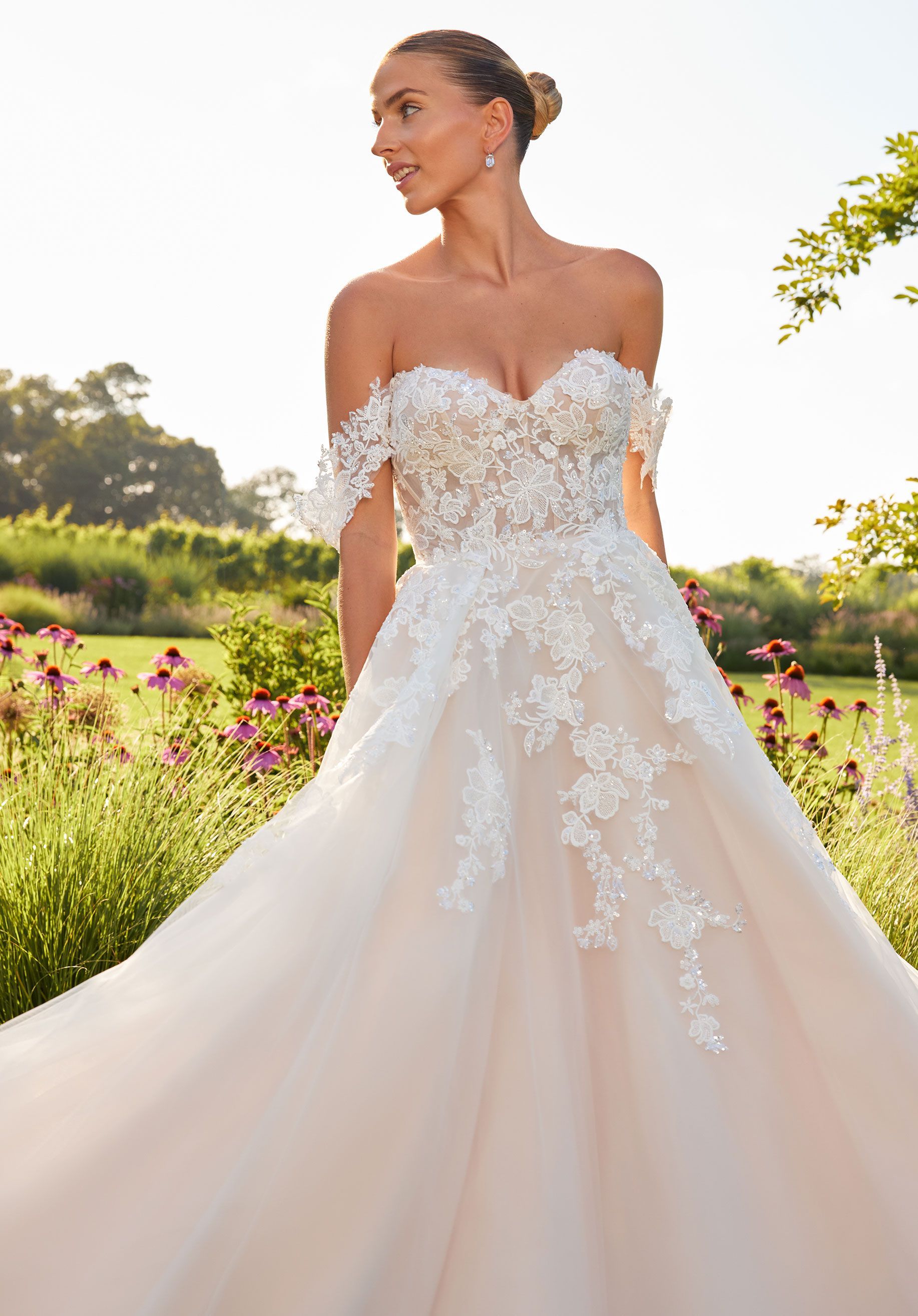 A woman in a wedding dress is standing in a field of flowers.