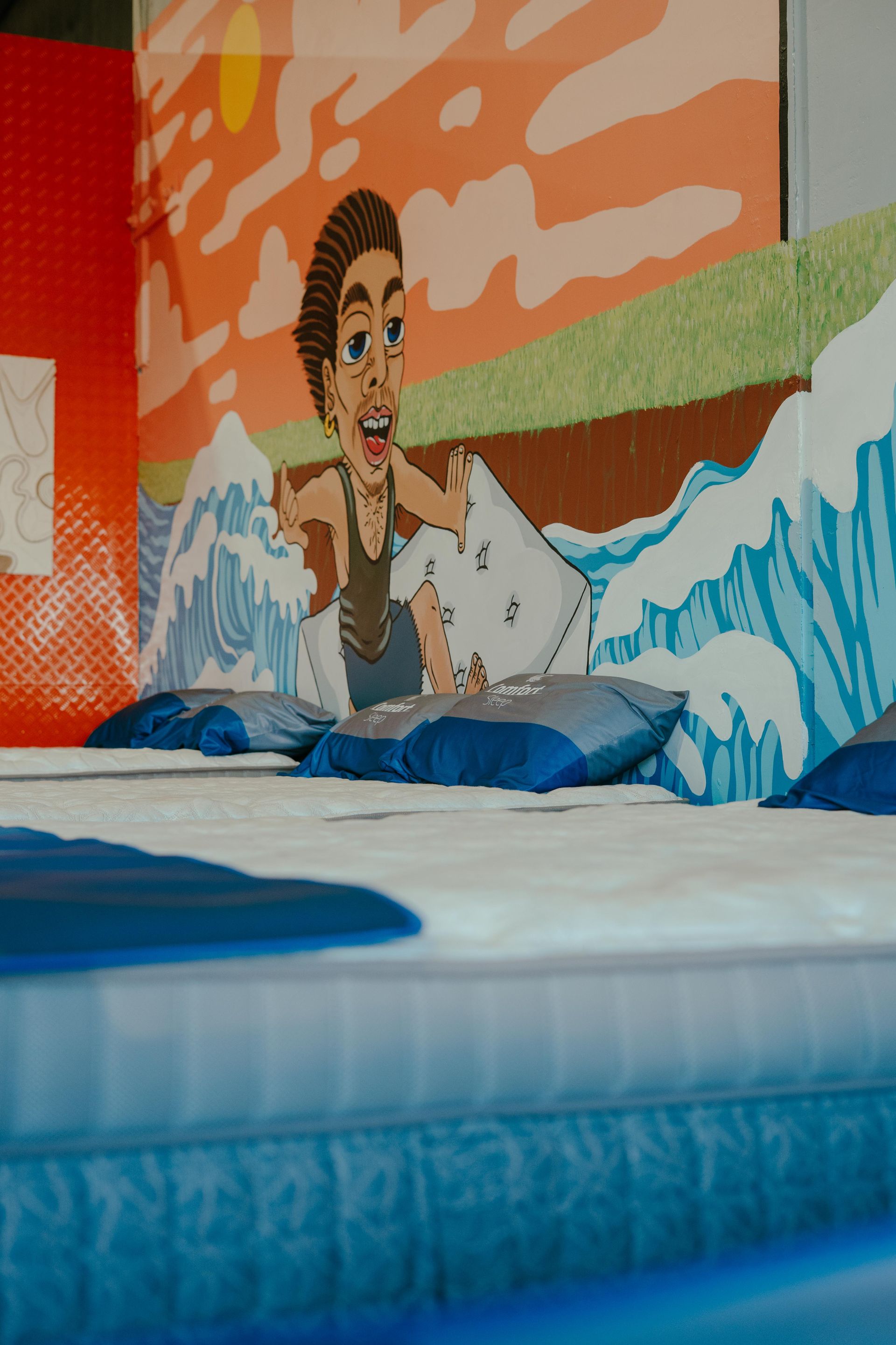 Cartoon Figure Standing in Front of Waves Painted on a Wall — Coastal Mattress' Direct in Brisbane, QLD  