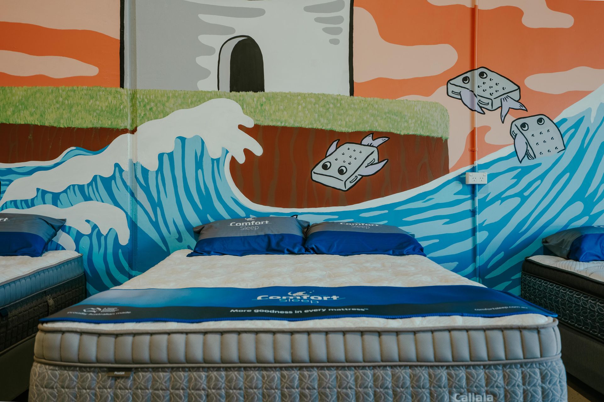 Mattress Showroom With Several Beds Displayed, Colorful Mural on the Wall — Coastal Mattress' Direct in Brisbane, QLD  