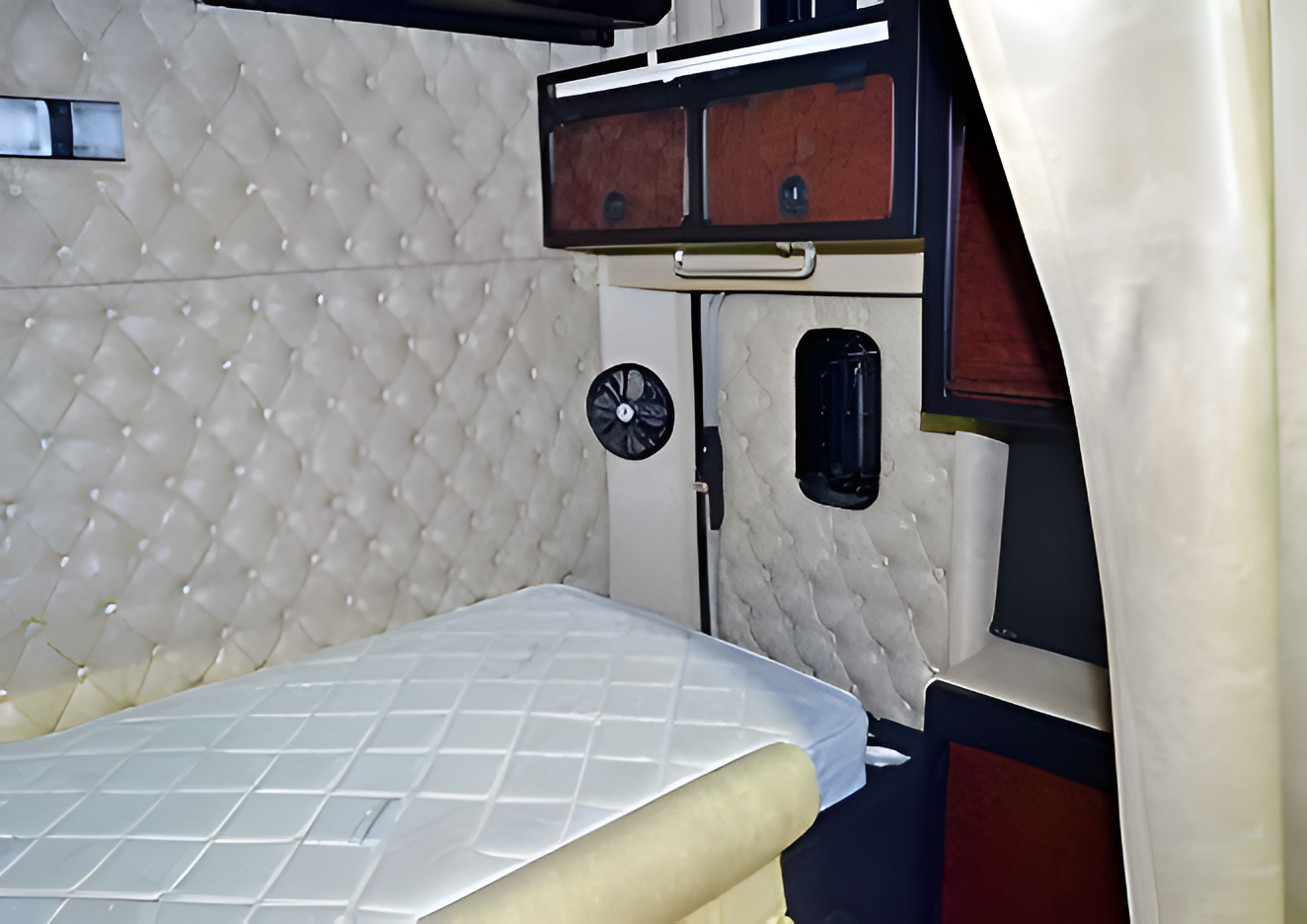 Interior of a Pop-up Camper With a Bed, Window, Curtains, and Wooden Cabinets — Coastal Mattress' Direct in South Nowra, NSW