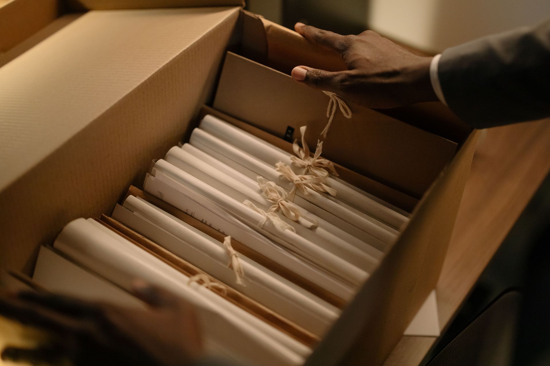 Hand placing white folders in an open cardboard box