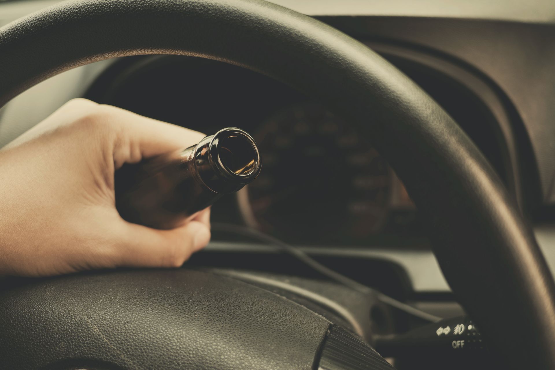 Driver holding a beer bottle behind the wheel before a DUI arrest.