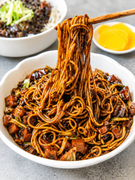 Plate of stir-fried noodles with vegetables and a lime wedge on a patterned dish