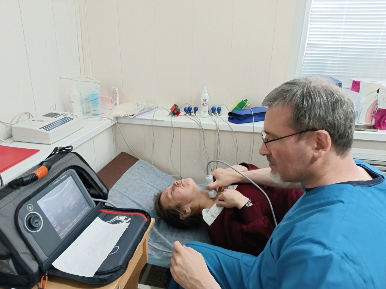 Dentist examining a patient in a clinic, using a handheld tool near the patient’s mouth.