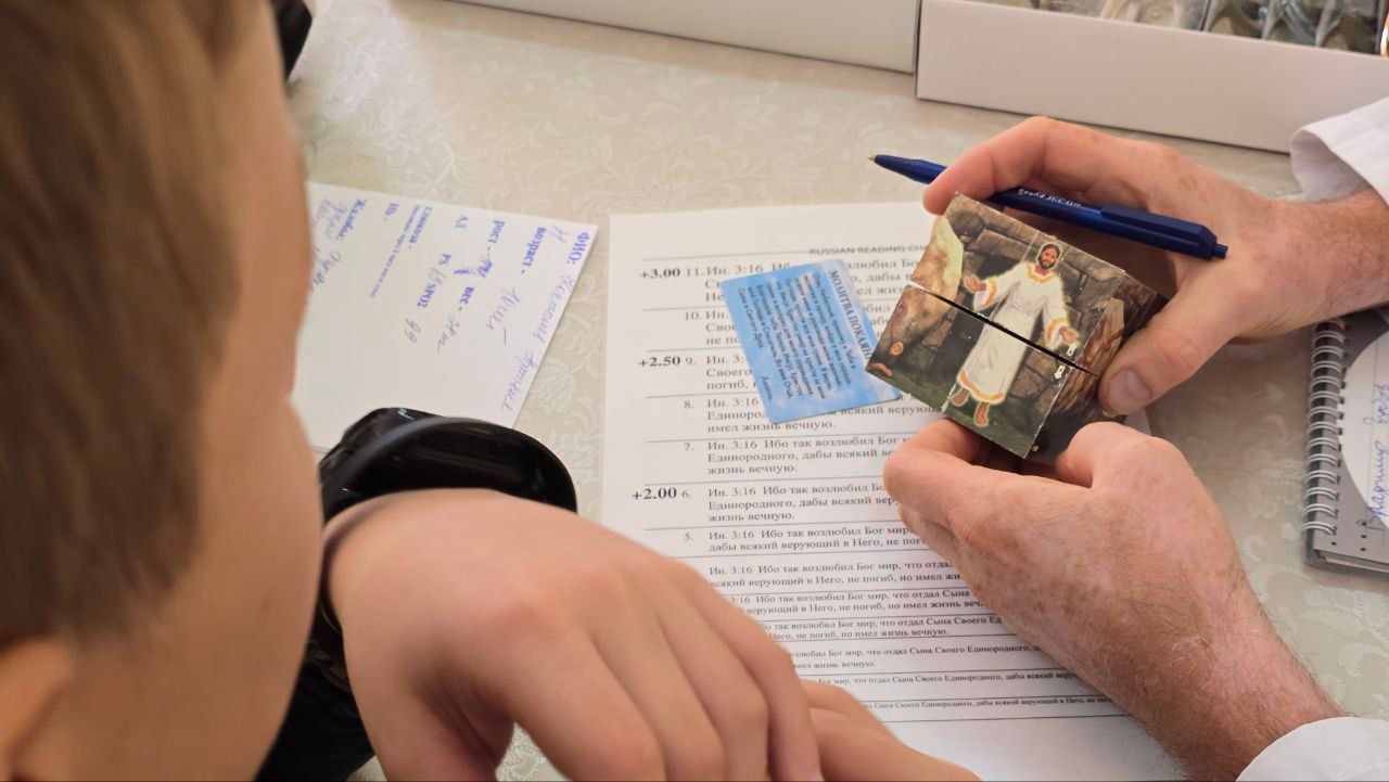 Hands and a child at a desk reviewing papers while holding a small stack of cash and a pen.