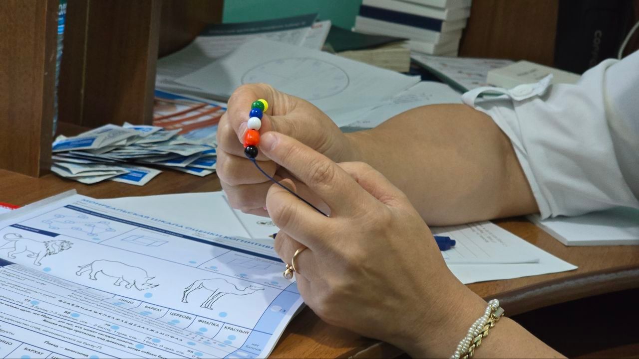 Hands holding a multicolored pen over paperwork on a desk with papers and folders nearby