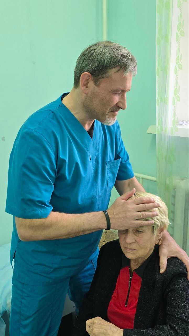 Healthcare worker checking a seated patient’s head in a bright clinic room
