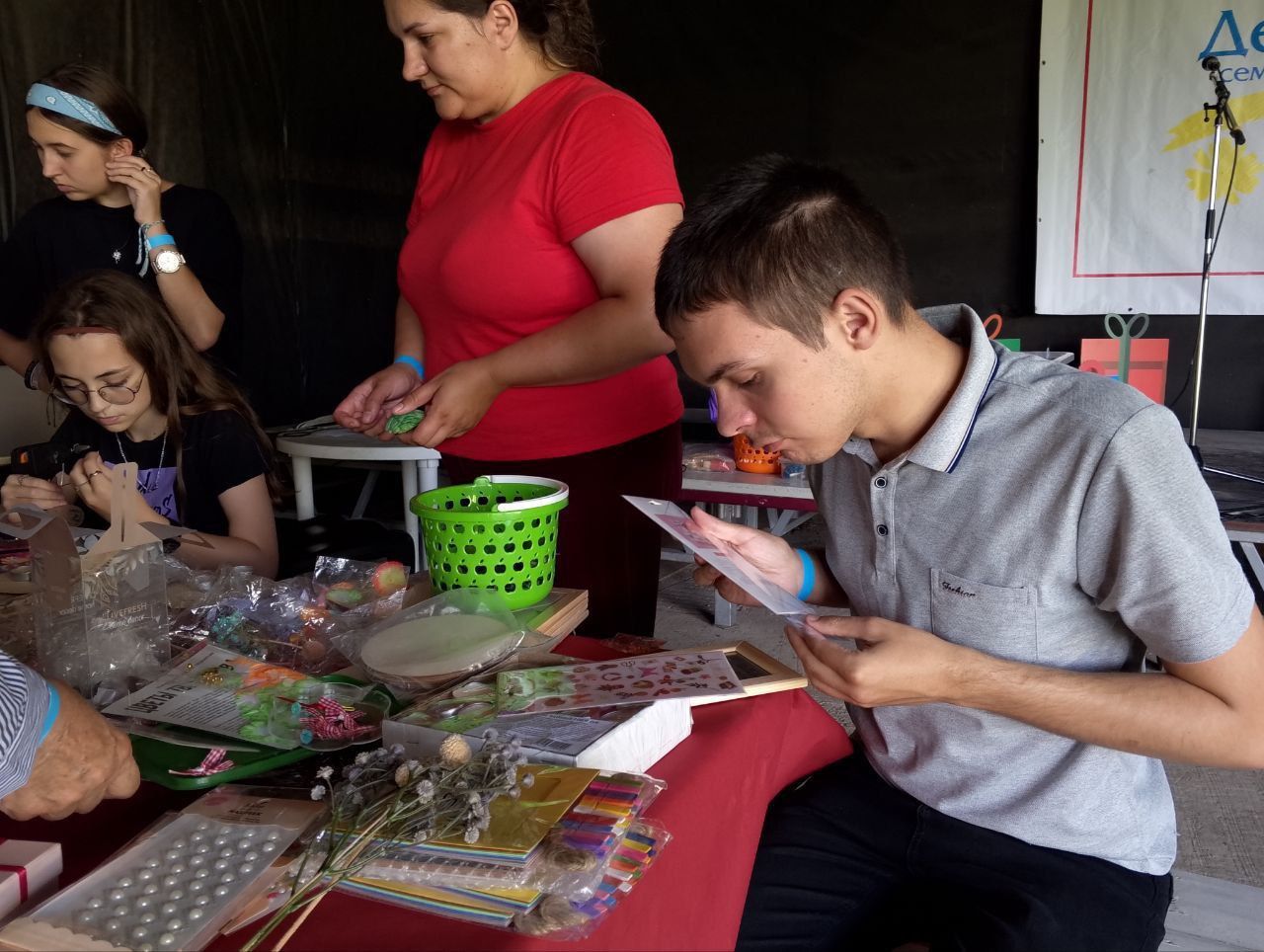 People gathered around a craft table, sorting colorful beads and supplies.